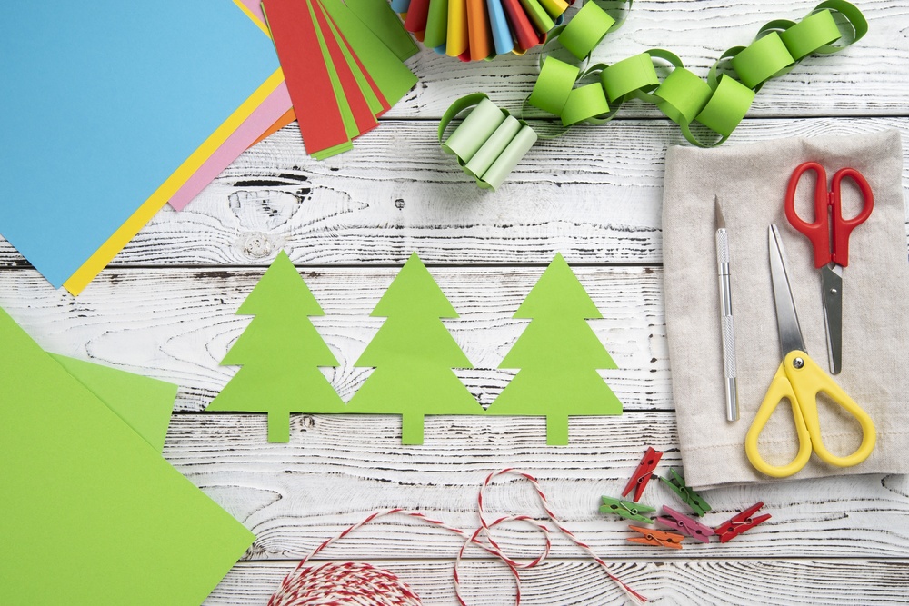 Manualidades navideñas con papel y herramientas creativas, mostrando adornos DIY como árboles de papel y guirnaldas. Una tendencia ecológica y personalizable para la decoración navideña 2024, ideal para añadir un toque artesanal y festivo al hogar.